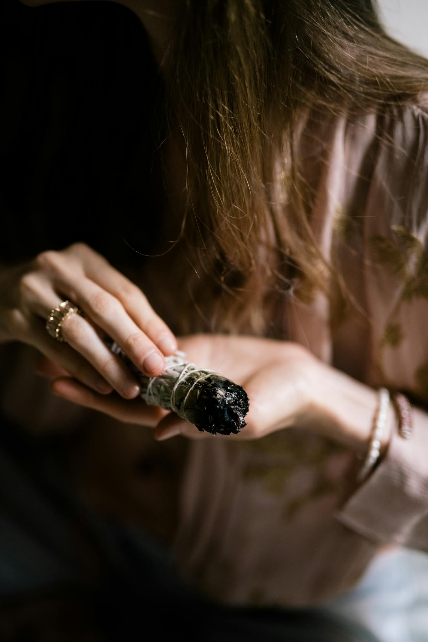A close-up of a woman holding and burning sage, emphasizing spiritual cleansing and healing rituals.
